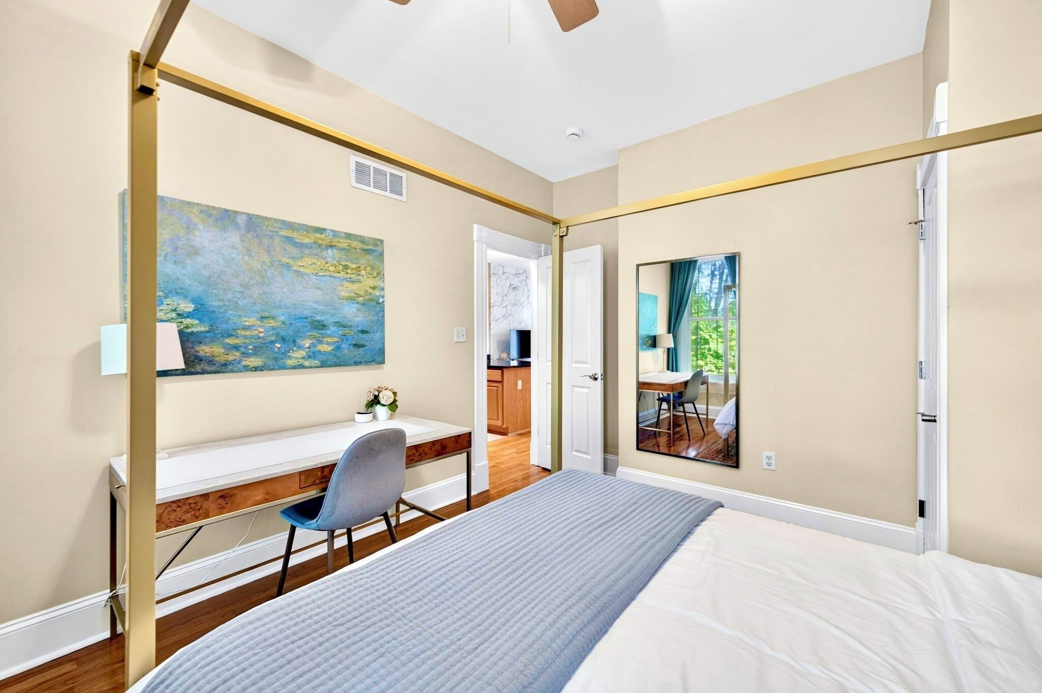 Une chambre à coucher avec un lit, un bureau, une chaise, un tableau et un miroir.