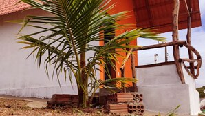 A building with a red roof, a palm tree, and a stack of bricks. - Chalé do Arisco (Cerro Corá)