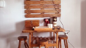 A wooden TV wall unit with a Netflix logo, a small wooden table, four stools, and a coffee mug. - Chalé do Arisco (Cerro Corá)