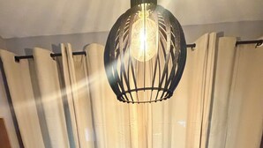 A dining table set for two with chairs, a vase with flowers, and a hanging light fixture. - Ceará Corner - Apartment on Futuro Beach (Fortaleza)