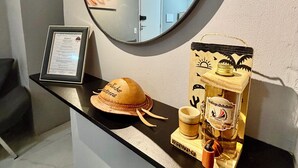 A reception desk with a mirror, a framed certificate, a hat, a bottle of liquor, and a wooden box. - Ceará Corner - Apartment on Futuro Beach (Fortaleza)