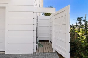 Eine weiße Außenwand mit einer Tür, einem kleinen Fenster und einem Gartenschlauch.