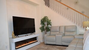 Un salon équipé d’un téléviseur à écran plat, d’une cheminée, d’un canapé et d’un escalier.