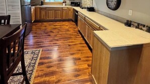 Une cuisine avec des meubles en bois, un parquet en point de Hongrie et une horloge au mur.