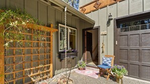 Une maison avec une clôture en bois, un porche avec une chaise et une porte de garage.