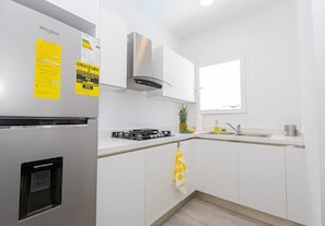 A modern kitchen with white cabinets, a stainless steel range, a water dispenser, and a window providing natural light.
