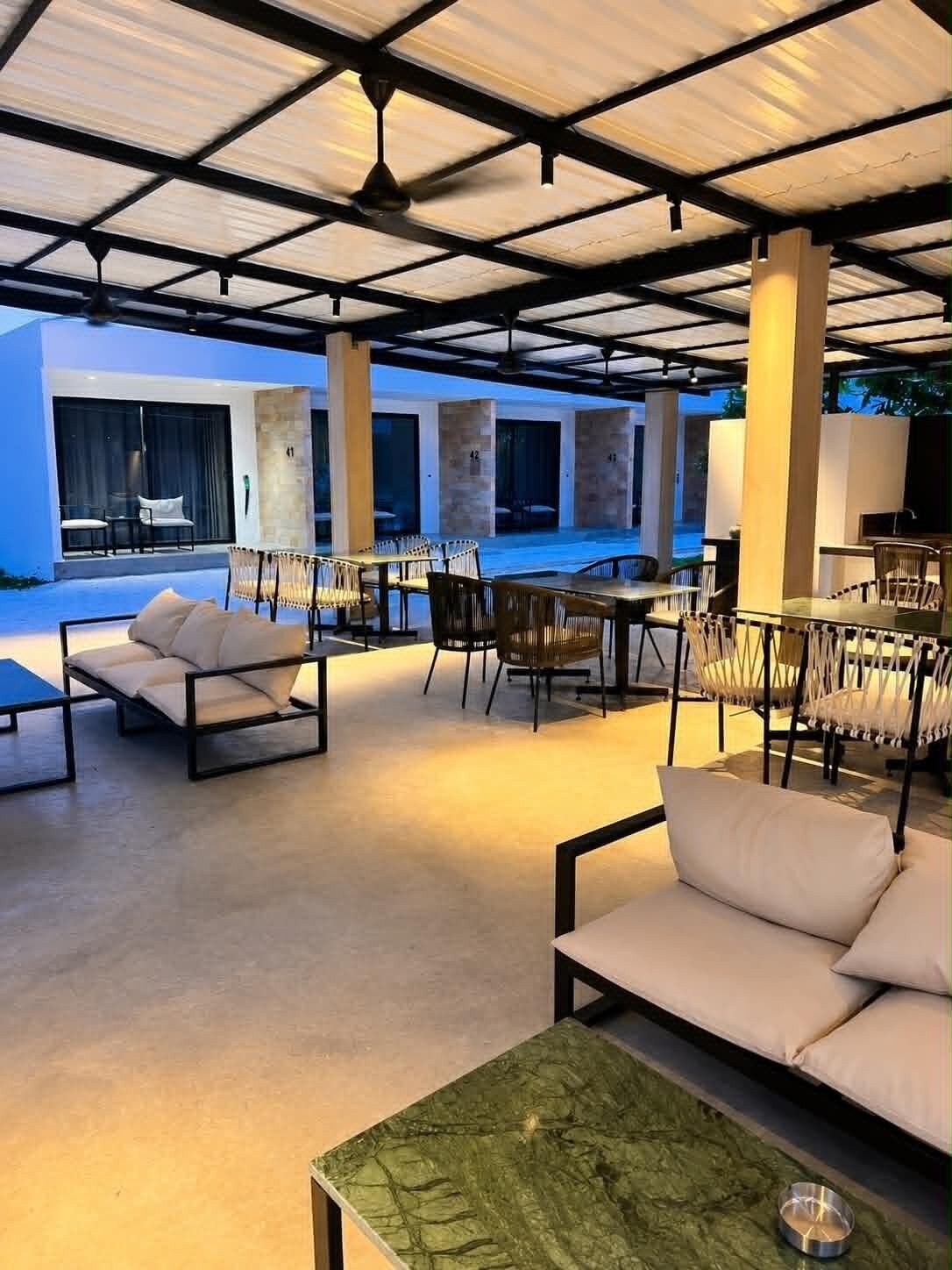 Un espace extérieur aménagé avec des tables et des chaises, un canapé et un ventilateur de plafond.