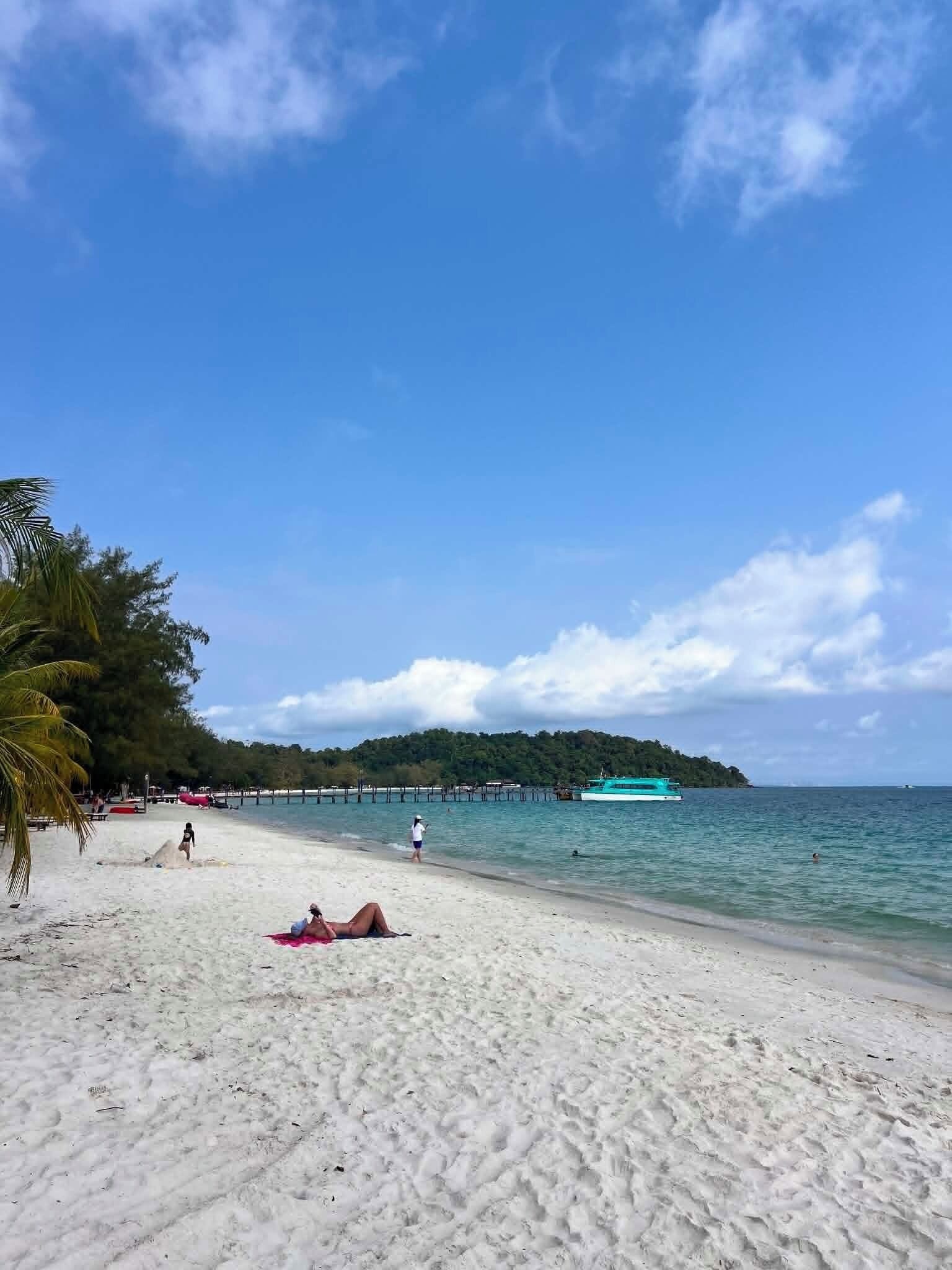 A beach with white sand, clear blue water, and a distant island.