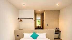 A modern hotel room with a large bed, a built-in bench, a small bathroom, and a view through an open doorway. - ARIMATABE Beachfront Resort (Koh Rong)