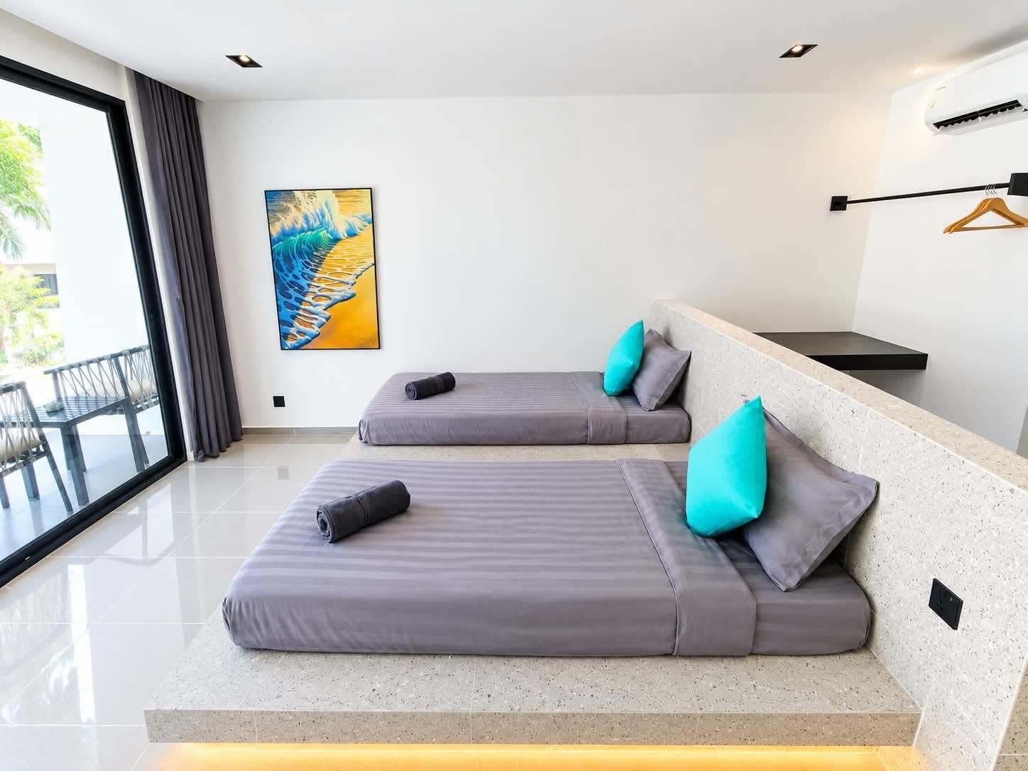 A modern room with two beds, a large window, and a painting on the wall.