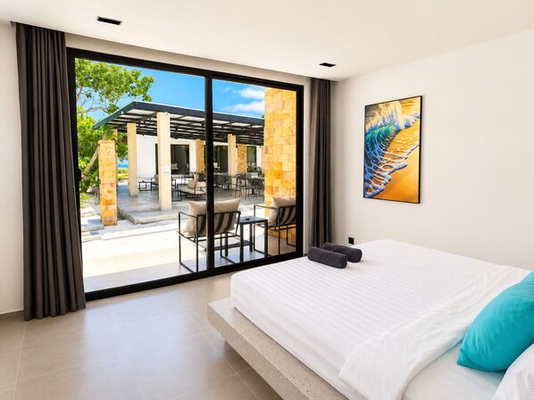 A hotel room with a large bed, a view of an outdoor patio, and a painting on the wall.