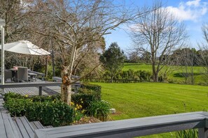 Eine Terrasse mit Gartenmöbeln, einem Baum und einem gepflegten Rasen.