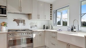 Una cocina moderna con electrodomésticos de acero inoxidable, armarios blancos y un ventanal que proporciona luz natural.