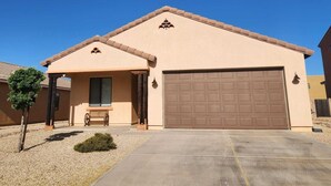 A single-story house with a garage, a small porch with a bench, and a clear blue sky. - Sierra Vista Hideaway / 5 minutes to Fort Huachuca (Sierra Vista)