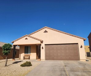 A single-story house with a garage, a small porch with a bench, and a clear blue sky. - Sierra Vista Hideaway / 5 minutes to Fort Huachuca (Sierra Vista)