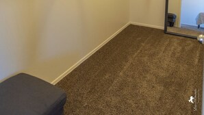 A room with a carpeted floor, a hanging rod, and a mirror reflecting a chair and a bed. - Sierra Vista Hideaway / 5 minutes to Fort Huachuca (Sierra Vista)