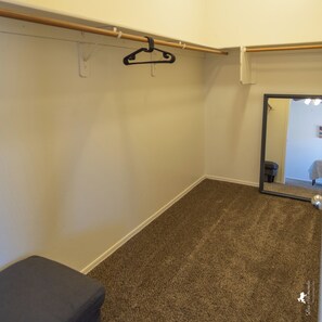 A room with a carpeted floor, a hanging rod, and a mirror reflecting a chair and a bed. - Sierra Vista Hideaway / 5 minutes to Fort Huachuca (Sierra Vista)