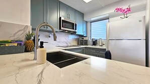 Una cucina moderna con lavello in acciaio inossidabile, forno a microonde, forno integrato e frigorifero.
