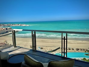 Ein Balkon mit Blick auf den Strand, einen Pool und einen entfernten Steg.