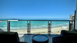 A balcony with wicker furniture overlooking a beach and ocean. - Cozy Oceanfront 1BR Studio Sonoran Star (Puerto Peñasco)