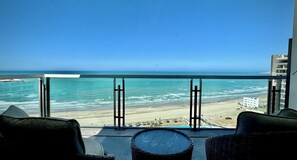 A balcony with wicker furniture overlooking a beach and ocean. - Cozy Oceanfront 1BR Studio Sonoran Star (Puerto Peñasco)