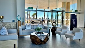 A modern lobby with a sofa, armchairs, a coffee table, and a glass wall with an exit sign. - Cozy Oceanfront 1BR Studio Sonoran Star (Puerto Peñasco)