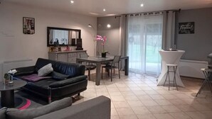 Een moderne woonkamer met een bank, eettafel en een keukenhoek.