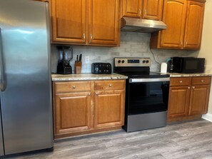 A kitchen with wooden cabinets, stainless steel appliances, a toaster, and a microwave.