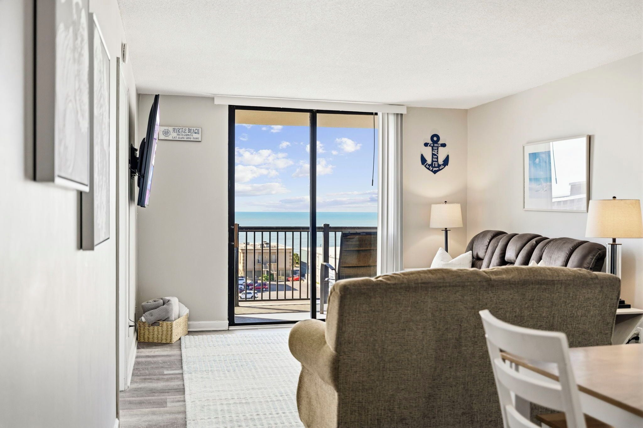 Ein Zimmer mit Blick auf den Strand, ein Ledersofa, ein Esstisch und eine Lampe.