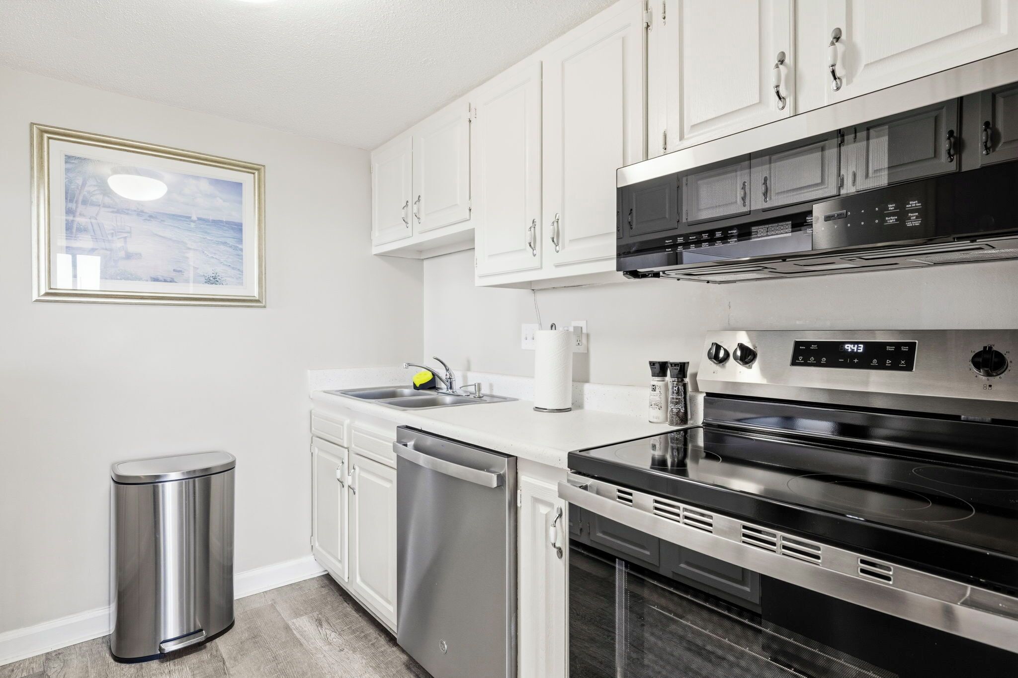 A modern kitchen with stainless steel appliances, white cabinetry, and a dishwasher.