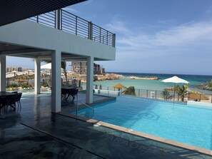 A pool area with a view of the ocean, a covered seating area, and a building under construction in the background. - Velvet at Paradisiac/Private Beach, Pool & Gated Luxury (Llandovery)