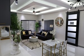 A modern living room with a sofa set, a coffee table, and a dining area with chairs. - Velvet at Paradisiac/Private Beach, Pool & Gated Luxury (Llandovery)