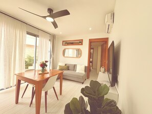 Ein Wohnzimmer mit Esstisch, Sofa und großen Fenstern.