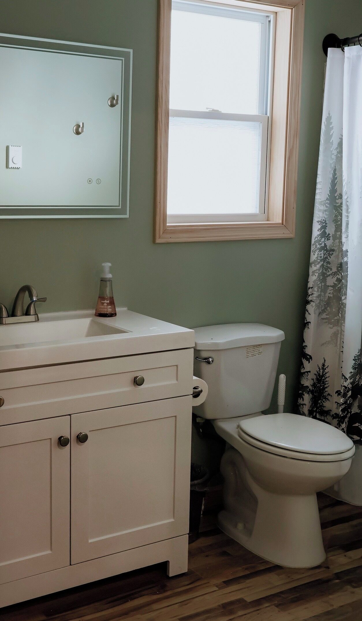 Une salle de bain avec un lavabo blanc, des toilettes, une fenêtre et un rideau de douche.