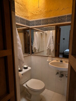 Un baño con inodoro, lavamanos y espejo.