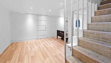A room with a wooden floor, a staircase with brick steps, and a white door.