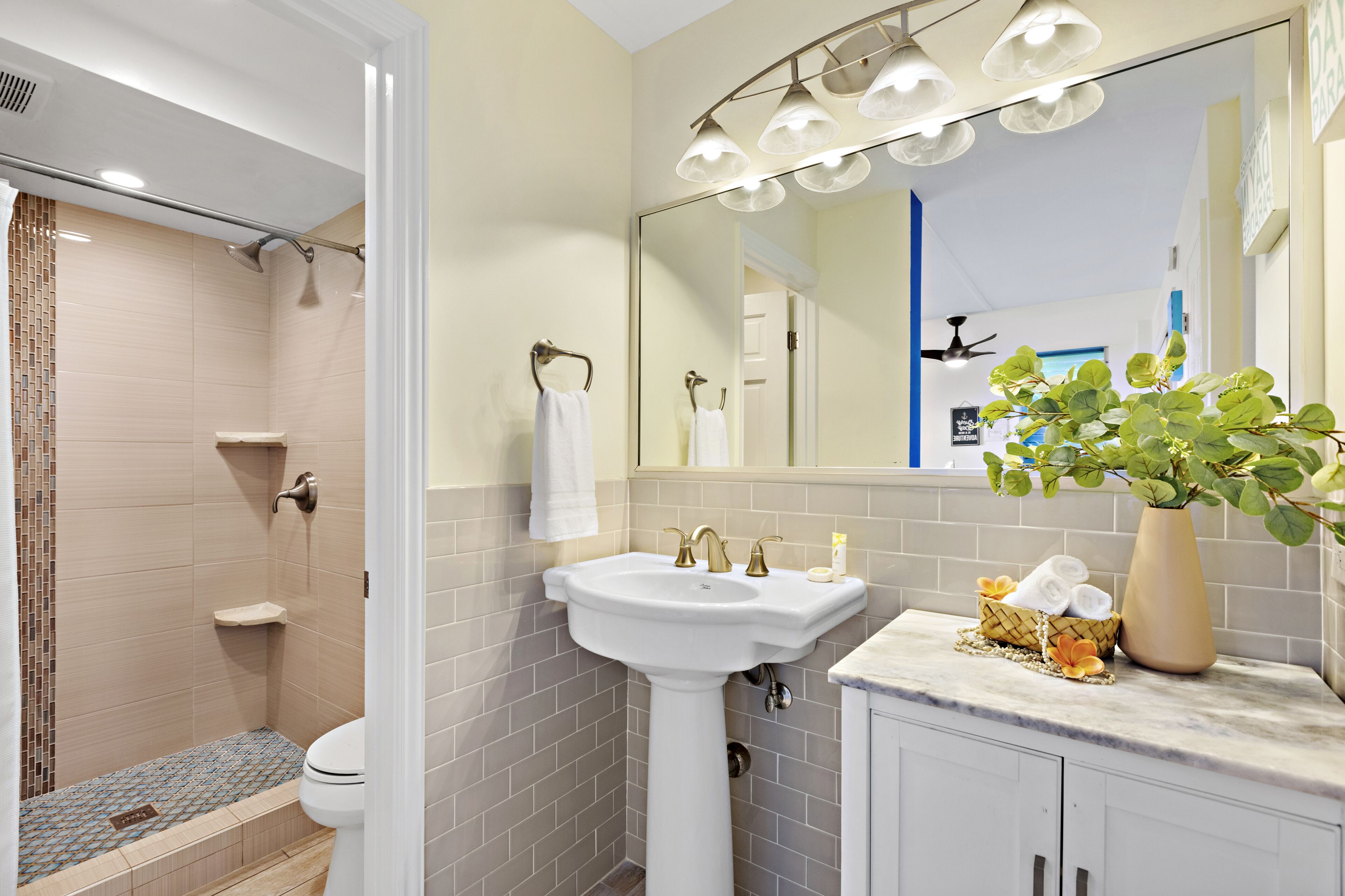 A bathroom with a shower, sink, and mirror.