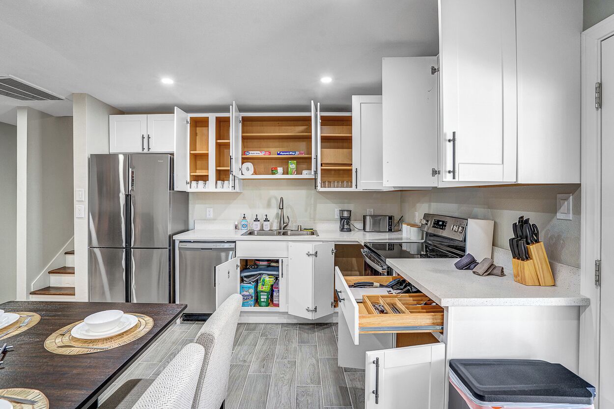 A modern kitchen with white cabinets, a stainless steel refrigerator, a microwave, and a coffee maker.