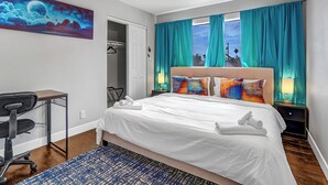Habitación de hotel con cama, escritorio, silla y un cuadro en la pared.