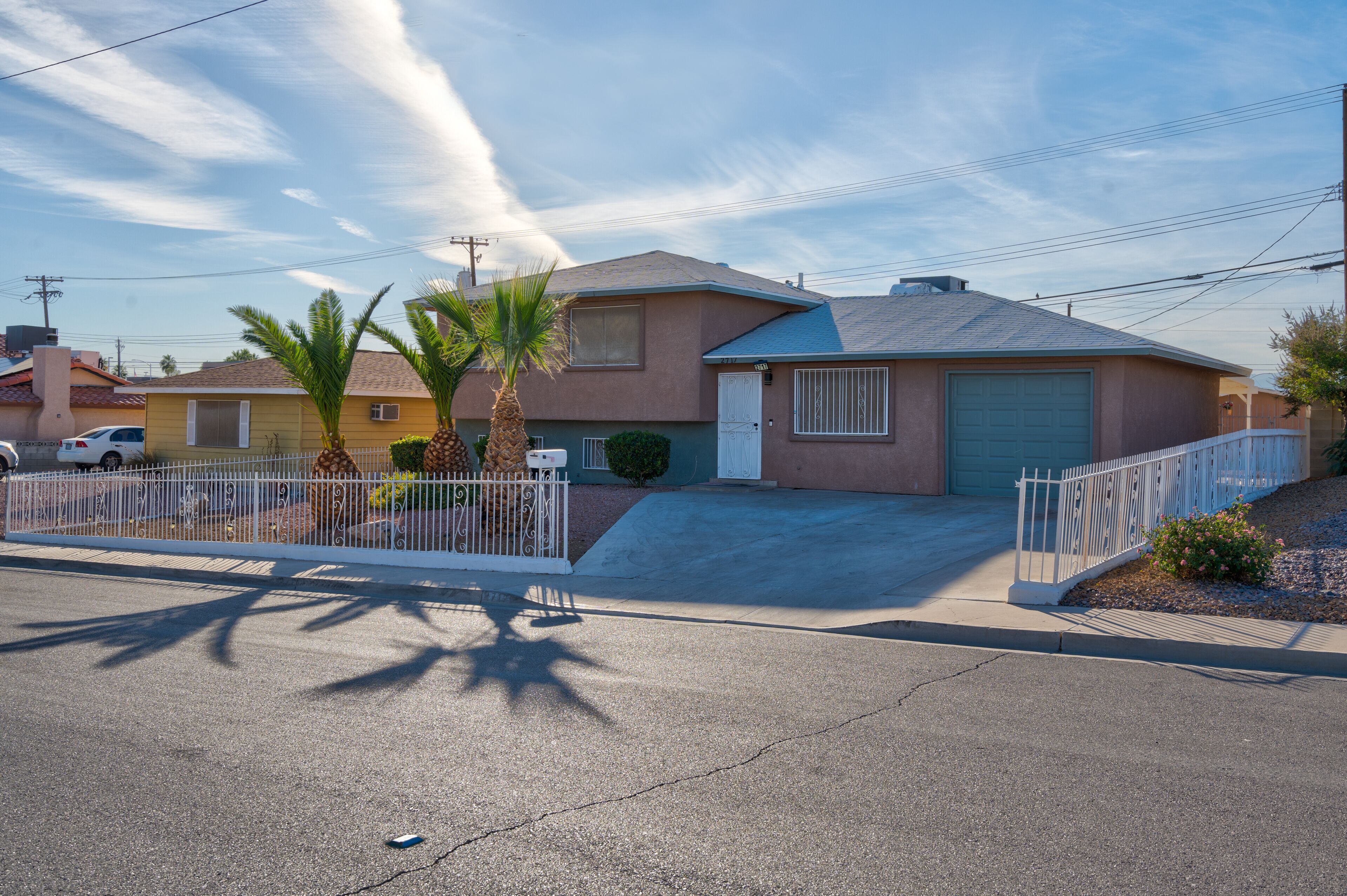 A residential house with a garage, a driveway, and a white fence.