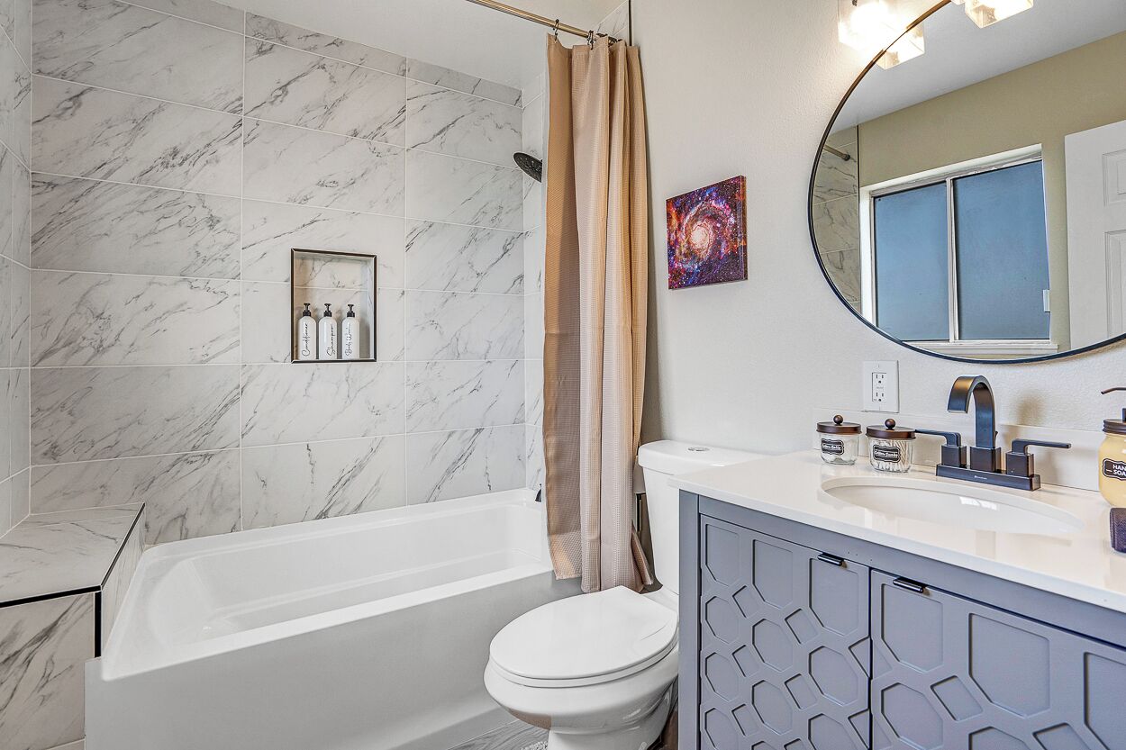 Een badkamer met bad, toilet en wastafel met spiegel.