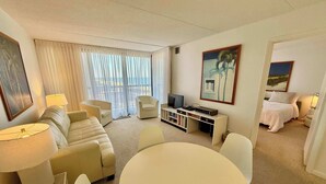 Habitació d'hotel amb sofà, cadires, televisor, taula petita i llit.