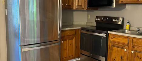 Una cocina con armarios de madera, electrodomésticos de acero inoxidable y piso de madera.