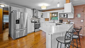 Una cocina moderna con electrodomésticos de acero inoxidable, una isla central con taburetes altos y paneles de madera en las paredes.