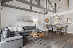 Una sala moderna con un sofá modular, una mesa de centro redonda y un comedor con sillas y una mesa.