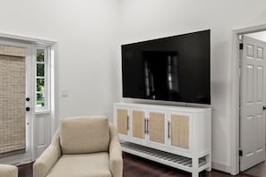 A room with a white entertainment center, a beige sofa, and a door with a window. - Fully Renovated 4 Bed/3 Bath Home - Walk to Stadium & Downtown (Tuscaloosa)