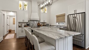 Una cucina moderna con una grande isola, elettrodomestici in acciaio inossidabile e un lavello in stile rustico.