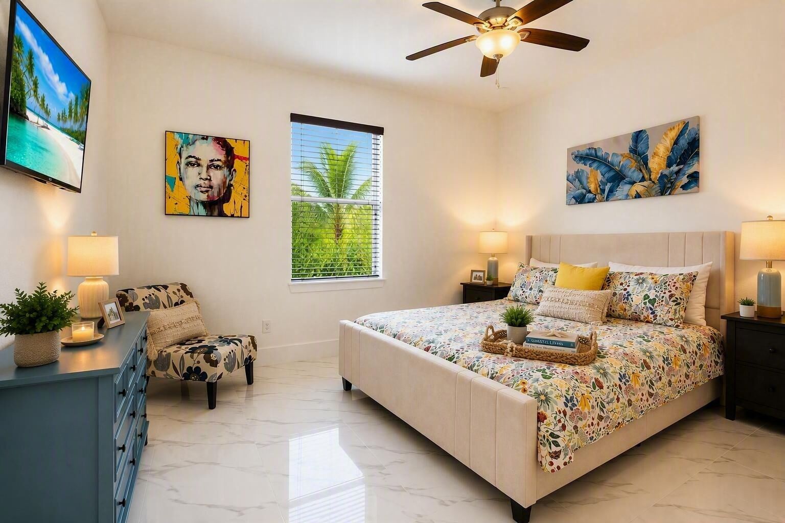 A bedroom with a bed, a desk, a chair, a ceiling fan, and artwork on the walls.