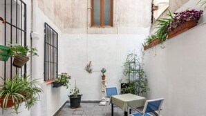 A narrow courtyard with a table and chairs, potted plants, and a window. - Madrid Centro - 3 bedroom and 2 bathroom apartment with 2 terraces (Ciudad de Madrid)