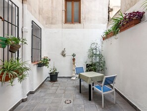 A narrow courtyard with a table and chairs, potted plants, and a window. - Madrid Centro - 3 bedroom and 2 bathroom apartment with 2 terraces (Ciudad de Madrid)